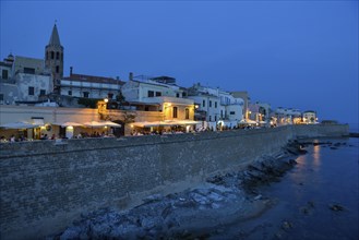 Row of houses, restaurants and city wall, twilight, Alghero, Sassari Province, Sardinia, Italy,