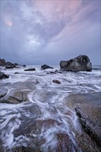 Rocks on beach of fjord of Norwegian sea in winter on sunset. Utakliev beach, Lofoten islands,