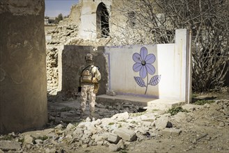 Ein Soldat steht vor einer an die Wand gemalten Blume im zerstoerten Stadtzentrum von Sinjar, 09.03