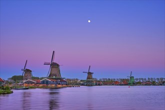 Windmills at famous tourist site Zaanse Schans in Holland in twilight on sunset with moon. Zaandam,