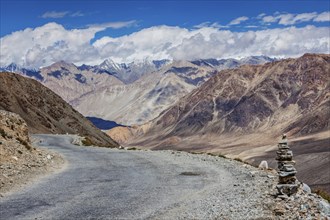 Road in Himalayas near Kardung La pass with stone cairn. Ladakh, India, Asia