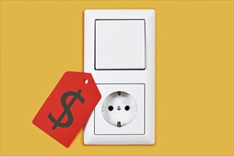 Electricity price rate concept with plug socket and light switch with red price tag on yellow wall