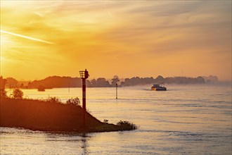 Cargo ships on the Rhine near Emmerich, early morning, sunrise, fog, mist on the river, North