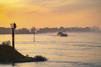 Cargo ships on the Rhine near Emmerich, early morning, sunrise, fog, mist on the river, North