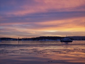 A beautiful sunset over the Oslofjord with a ferry approaching oslo