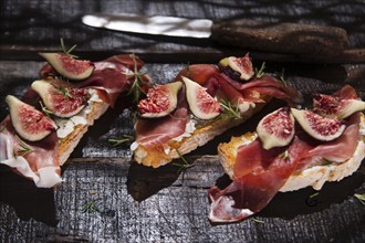 Presentation on wooden table bruschetta with figs and prosciutto