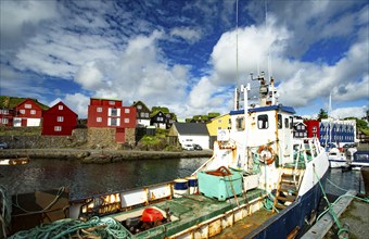 The photo shows a rusty fishing boat in a harbour