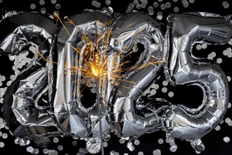 Happy new year 2025 metallic balloons with confetti and sparkler firework Bengal lights on dark