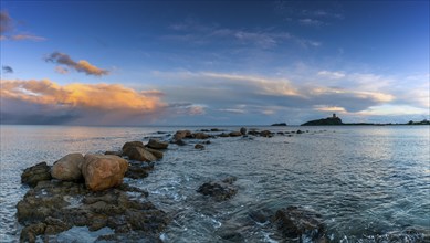 Panorama view of a colorful sunset at Nora Beach in Sardinia with the Coltellazzo Tower in the