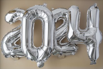 Silver foil number 2024 celebration new year balloon on neutral beige background. Happy New year