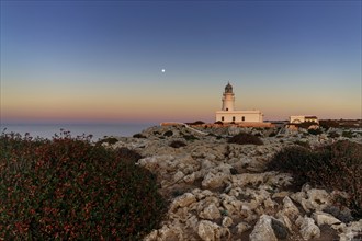 A view of the Cap de Cavalleria Lighthouse on Menorca at sunset with a full moon rising