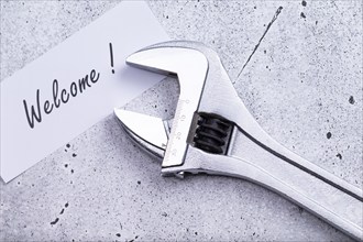 The photo shows a label with the inscription 'welcome' with a spanner on a grey background