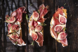 Presentation on wooden table bruschetta with figs and prosciutto