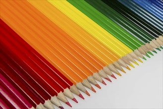 Abstract composition of a set wooden colour pencils against a white background