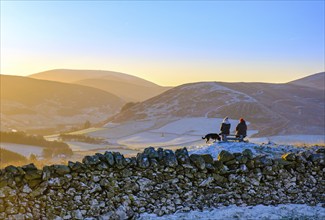 Two Friends Sitting On A Bench In The Beautiful Scottish Countryside After A Hike On A Frosty