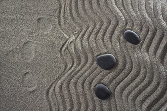 Drawings on light gray sand and black stones in a small Zen garden