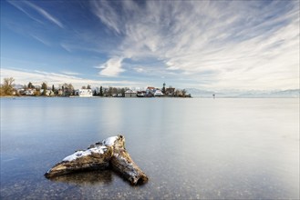 A peaceful lake with a log in the foreground with picturesque St George's Church on the lakeshore