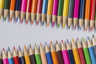 Abstract composition of a set wooden colour pencils against a white background