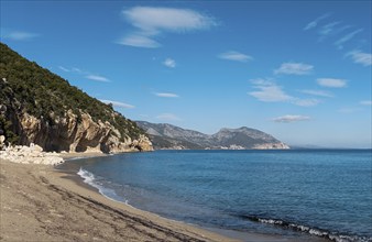 The overhanging cliffs and sandy beach at Cala Luna on the east coast of Sardinia