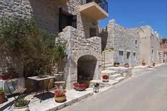 Charming stone alley with flowers in a sunny village, Geromilenas, Mani, Laconia, Peloponnese,