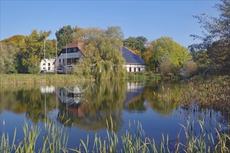 House on the lake with a clear reflection in the water, surrounded by autumnal nature, Fleesensee