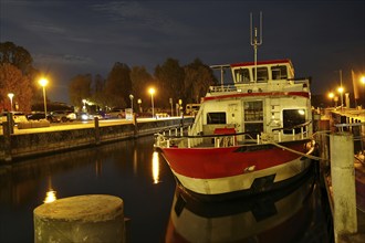 Illuminated excursion boat in the harbour at night, reflected in the calm water, Waren, Müritz,