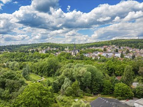 Idyllic village landscape with church surrounded by lush green forests and hills under a cloudy