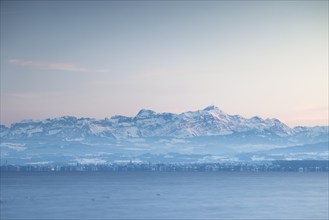 Snow-covered mountains in the Alpstein with Säntis in the background of a lake at dusk with wintry