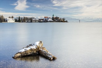 A peaceful lake with a log in the foreground with picturesque St George's Church on the lakeshore