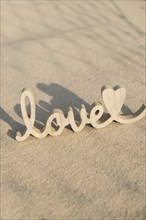 Wooden word love on sandy beach background. Concept of romantic holiday anniversary, proposal,