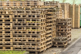 Many wooden pallets are stacked on top of each other and form a wall in a storage room