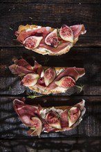 Presentation on wooden table bruschetta with figs and prosciutto