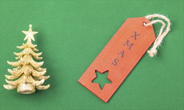 The image shows an golden x-mas tree with red label, isolated on green