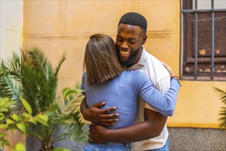 Multi-ethnic african and caucasian couple embracing and congratulating standing in the city