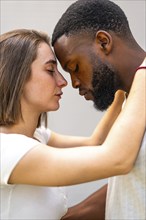 Close-up of multiracial lovers face to face with eyes closed embraced tenderly