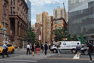 New York City, USA, June 20, 2018: People crossing street in Astor Place with Cooper Square against