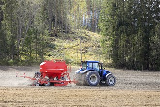 Working in field with blue Valtra tractor and Horsch Pronto 4DC seeder on a day of spring. Salo,