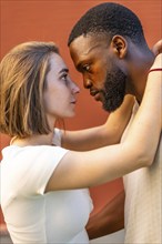 Vertical side view photo of a young African American man and a young Caucasian woman in love are