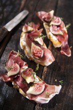 Presentation on wooden table bruschetta with figs and prosciutto