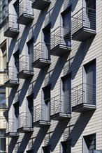 Many small balconies on a flat block cast long shadows in the evening light