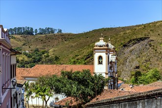 Tower of historic baroque church among the houses, roofs and hill in the city of Ouro Preto in