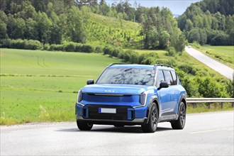 2024 blue Kia EV9 SUV car on road. Kia EV9 wins Red Dot Award: Product Design 2024 'Best of the