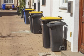 Various rubbish bins standing on the pavement in front of residential buildings, Hildesheim, Lower