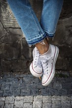 Low section of woman wearing sneakers sitting on the street