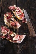 Presentation on wooden table bruschetta with figs and prosciutto