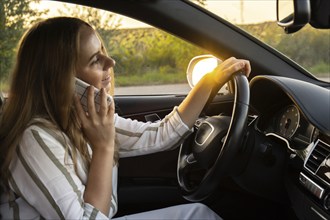 Happy young woman speaking by mobile phone while driving car. Business woman talking phone call in