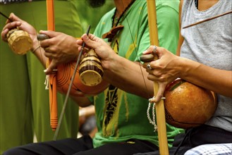 Musicians playing an Afro Brazilian percussion musical instrument called a berimbau during a