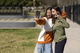 Two girls taking selfies in a park