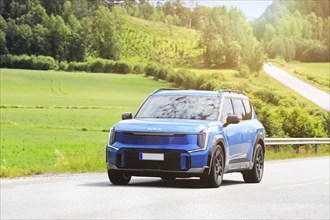 2024 blue Kia EV9 SUV car on road. Kia EV9 wins Red Dot Award: Product Design 2024 'Best of the