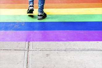 Feet Walking on Sidewalk Decorated with Rainbow Flag. Lesbian, Gay, Bisexual, Pansexual, Asexual,